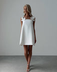 Elegant White Mini Dress with Floral Shoulder Detail.